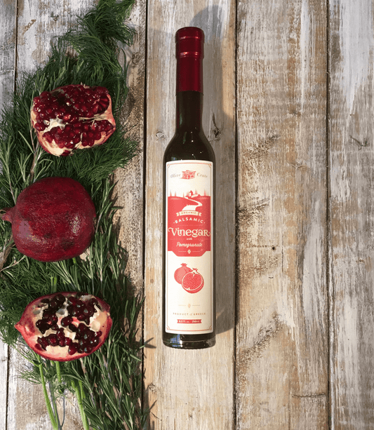 Organic balsamic vinegar with pomegranate in a glass bottle, rich amber color, produced by Olive Crate, ideal for salads and cooking.