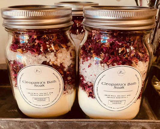 Onic Brands Cleopatra Bath Soak in a clear jar with rose and lavender flowers, showcasing luxurious herbal bath salts.