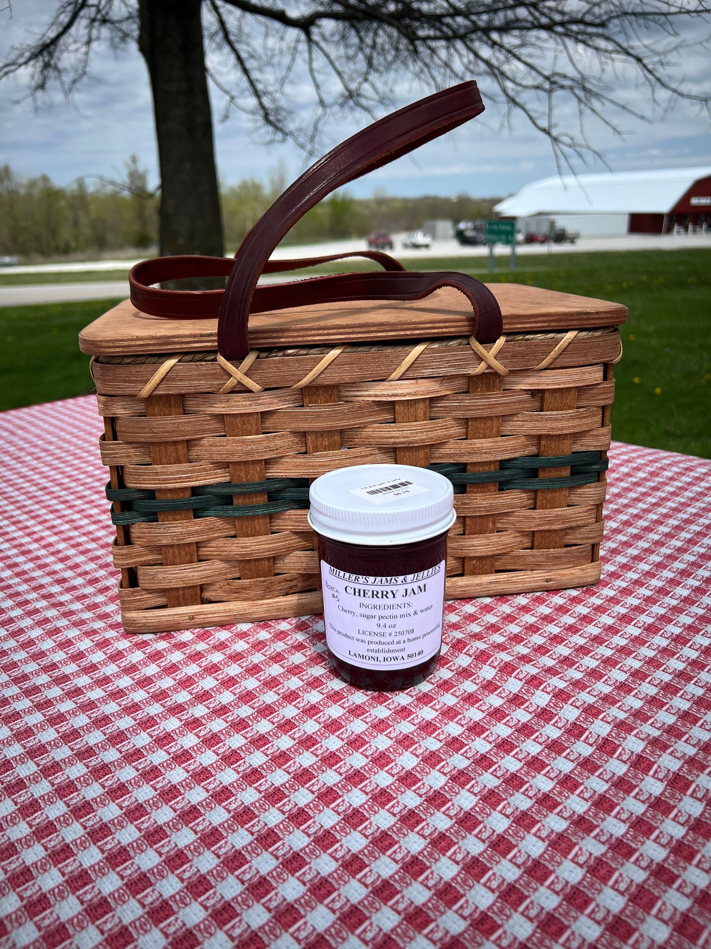 Jar of Miller's Cherry Amish jam from Amish Country Store, showcasing fresh cherries and vibrant label on a rustic background.