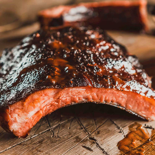 Limited edition Bourbon Barrel Smoked Ribs from Pig of the Month BBQ, showcasing juicy, glazed ribs with a smoky bourbon finish.