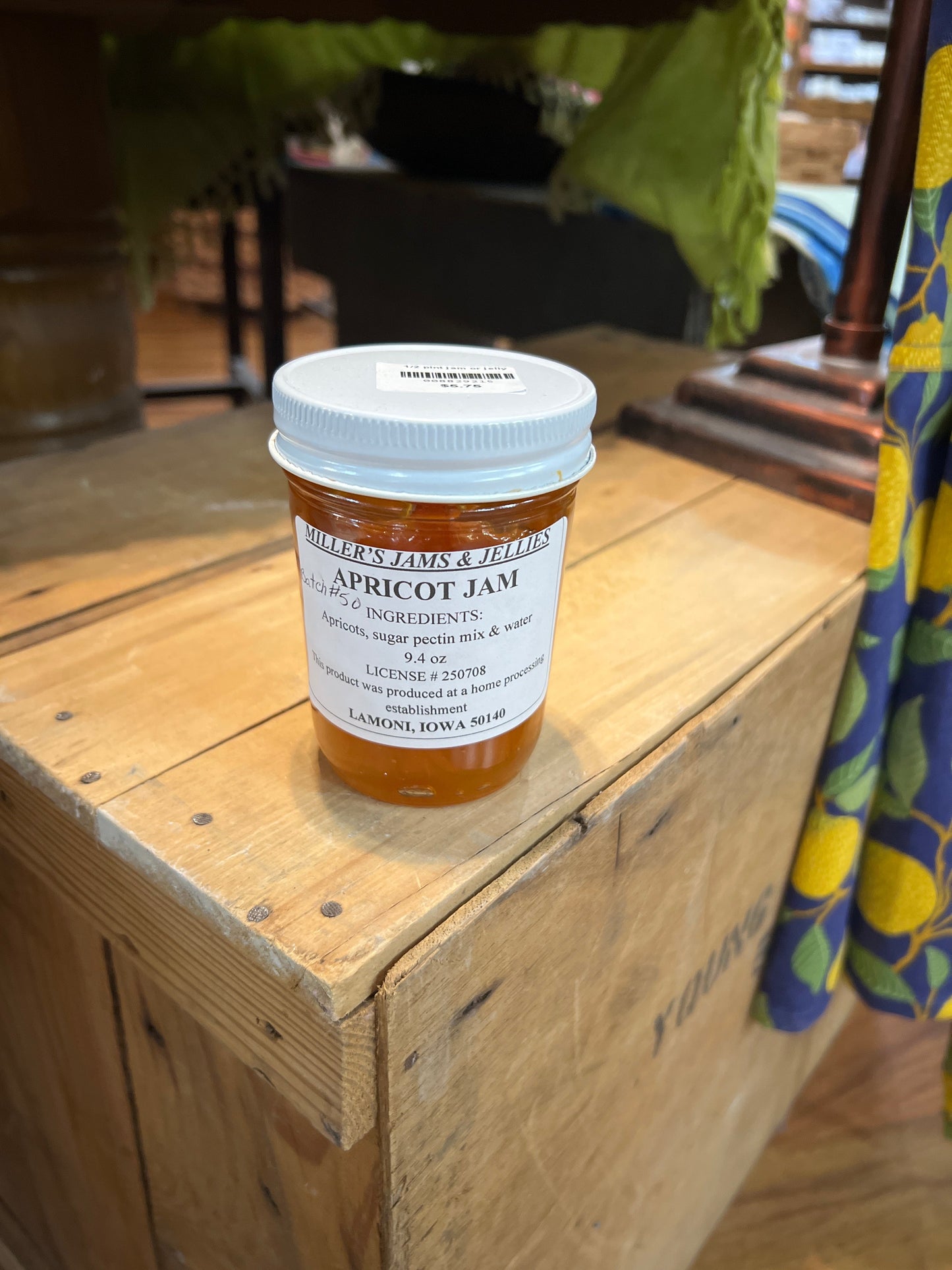 Jar of Amish Miller’s Apricot Jam with a golden-orange color, label featuring apricots, on a rustic wooden surface.