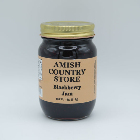 Canned Amish Country Store blackberry jam jar, 18 oz with a label, glossy lid, and fresh blackberry fruit visible inside.