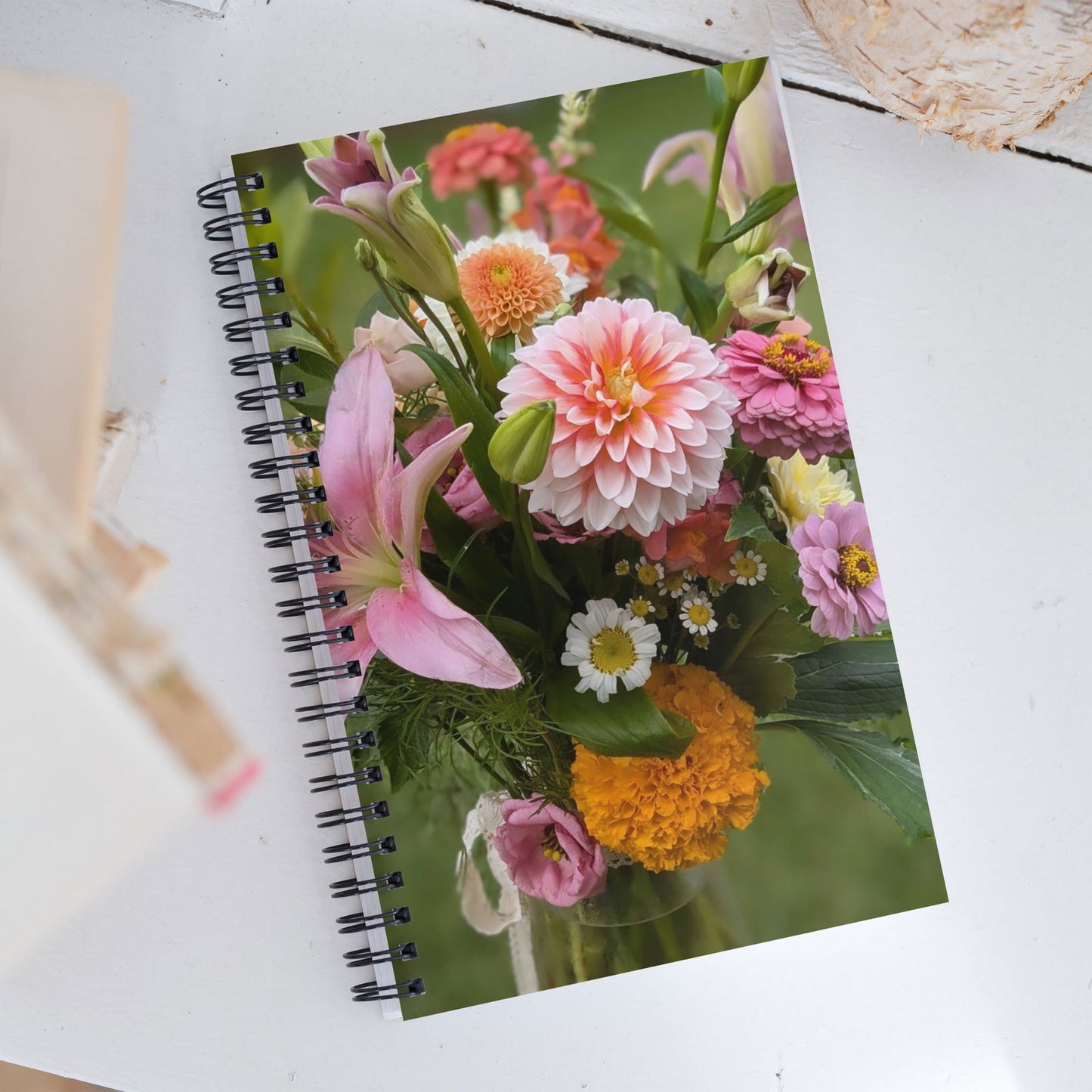 Spiral-bound notebook featuring a vibrant summer bouquet of lilies, dahlias, zinnias, and marigolds in a glass vase against a blurred green background