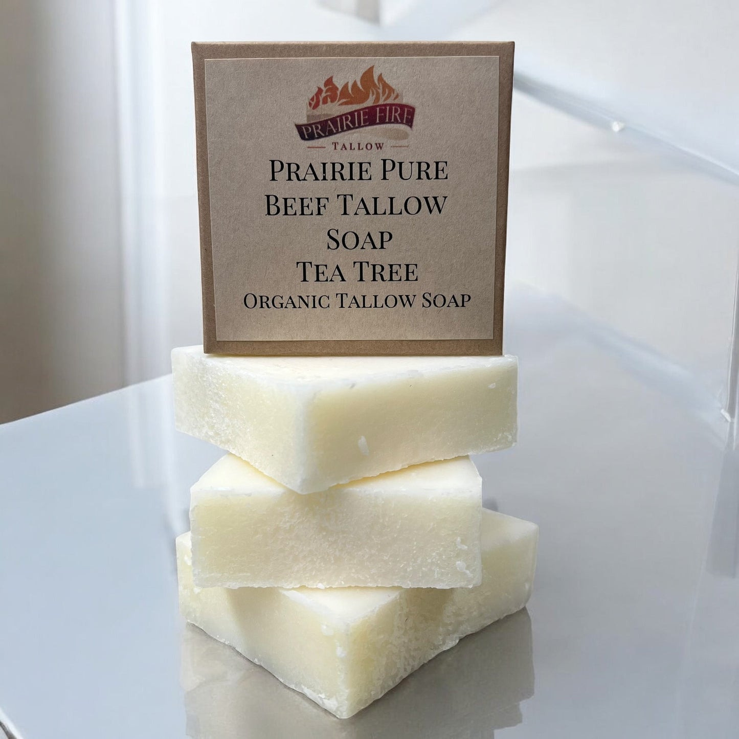 Three creamy white Prairie Fire Tallow Pure Beef Tallow Soap Bars are stacked on glass. The label highlights: Made in USA, grass-fed and finished, natural and organic, for face, body, and hair.