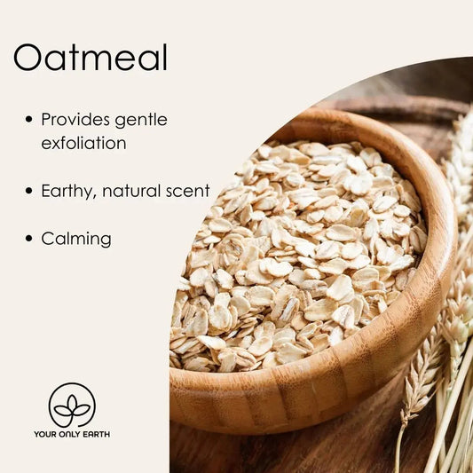 A wooden bowl filled with oatmeal sits on a wooden surface with oat sprigs. Benefits listed: Gentle exfoliation, Earthy scent, Calming. Enriched with organic oils for nourishment. A small logo reads YOUR ONLY EARTH, featuring the Happy Dog Soap Bar by Your Only Earth.