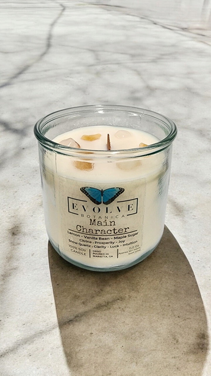 Evolve Botanica Rocks Candle featuring a citrine and snow quartz gemstone, with a wood wick soy candle against a neutral background.
