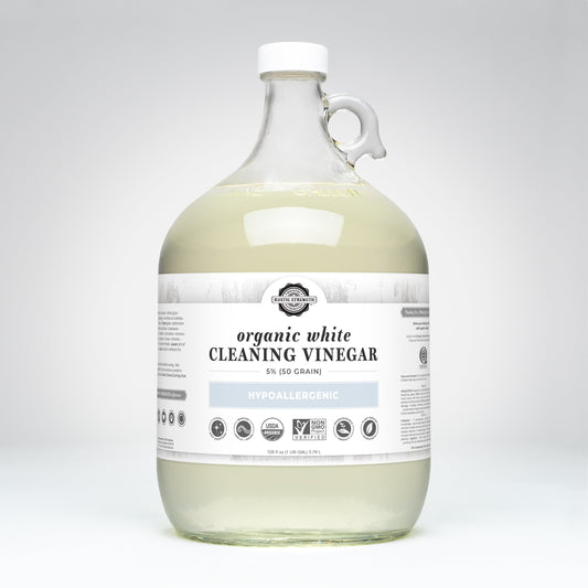 Rustic Strength Organic White Cleaning Vinegar | 5% (50 grain) comes in a clear, handled gallon jug. The hypoallergenic, biodegradable, non-GMO vinegar has various certifications noted on a white label.