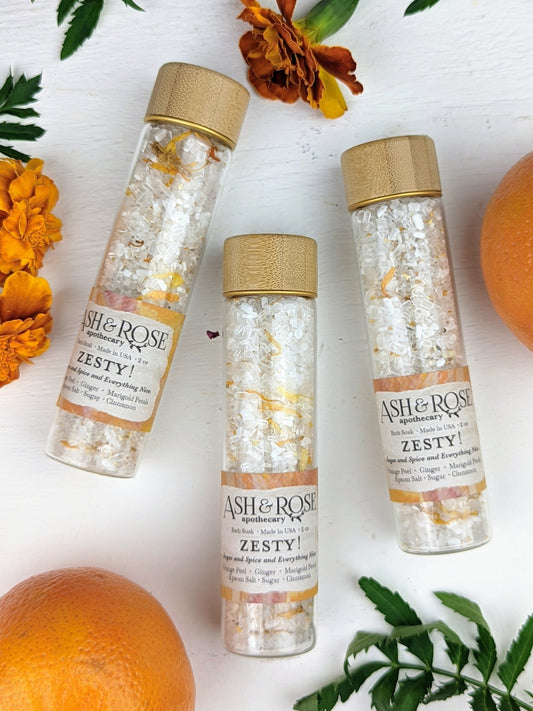 Ash & Rose Zesty Orange Ginger Bath Soak vial with vibrant orange and ginger ingredients, perfect for a soothing bath experience.