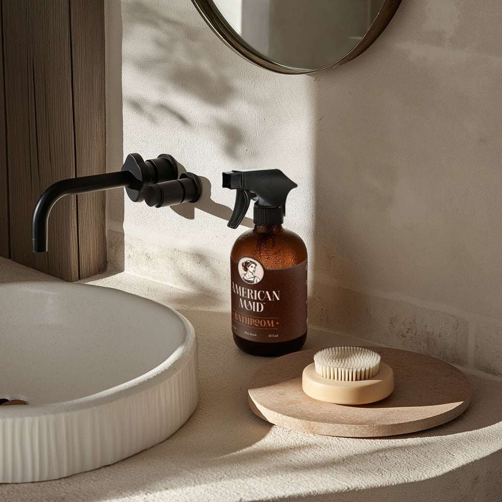 American Maid Daily Essentials Kit with bathroom cleaning supplies and tools arranged on a bathroom countertop.