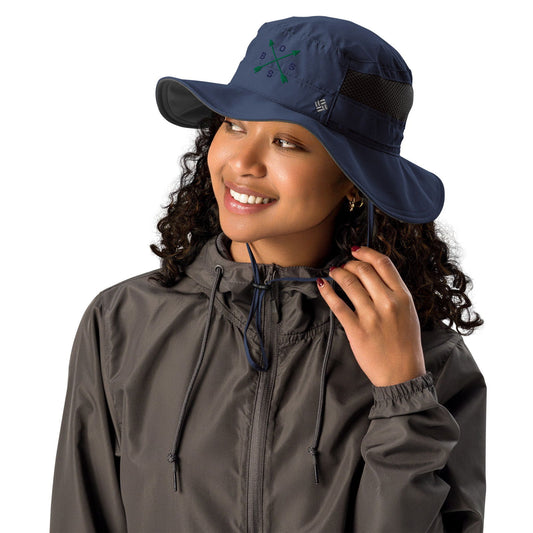 Columbia Sportswear sun hat model wearing a dark gray jacket featuring a navy blue hat with a compass rose design dark gray brim and dark maroon nails.