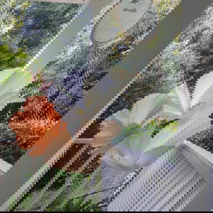 The image is heavily pixelated and distorted, but hints of green, white, orange, and gray suggest an outdoor scene with Blessings Grow Meadows Merch's RENTAL: Six Extra Large Free-Standing Paper Flowers (Metter, GA Pick-Up).