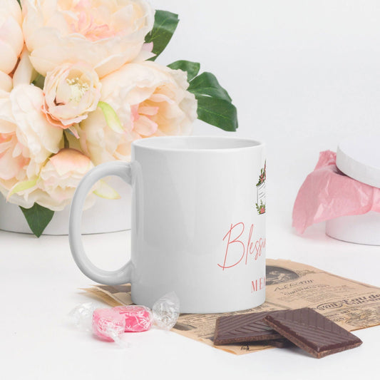 White glossy Blessings Grow Meadows mug with "Blessings Grow" design, 11 oz ceramic mug for hot beverages.