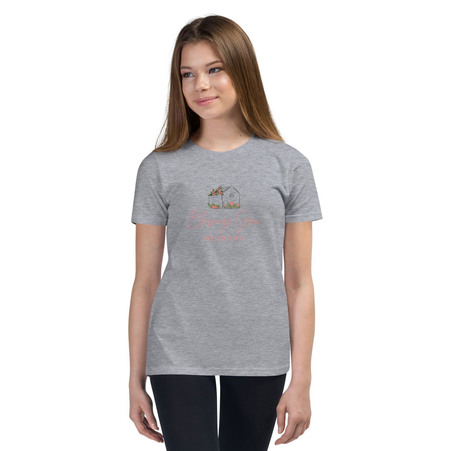 Apparel graphic design featuring a gray heather t-shirt with a drawing of a small house adorned with pink flowers and greenery a stylized script logo and soft coral text