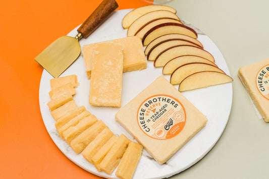 Block of 15-year-aged cheddar cheese from Cheese Brothers, Inc., showcasing its rich, firm texture and deep orange color.