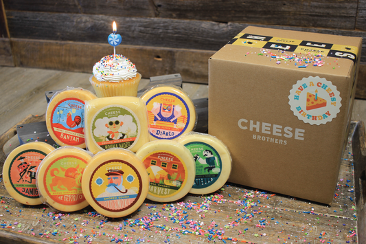 Cheese Brothers, Inc. "Have a Cheesy Birthday" gift basket with assorted cheeses and snacks in a decorative bundle.
