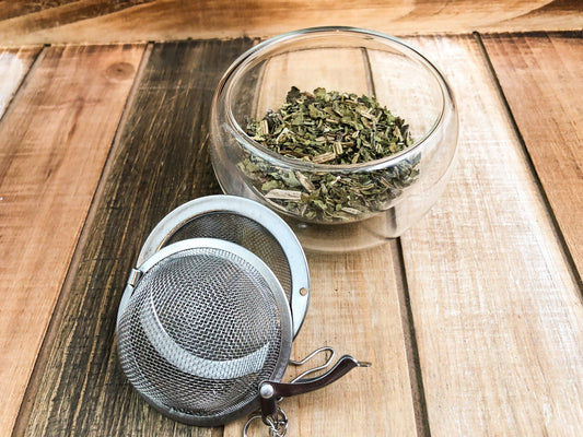 Dried comfrey herb from HerbalRoseApothecary, showing green leaves and stems in a natural, rustic setting.