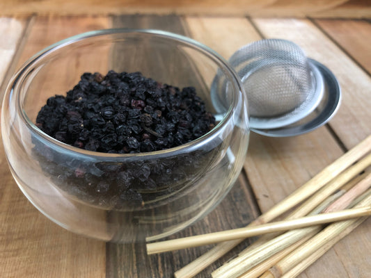 Dried organic elderberries from HerbalRoseApothecary, close-up of plump, dark purple elderberries in a natural herbal setting.