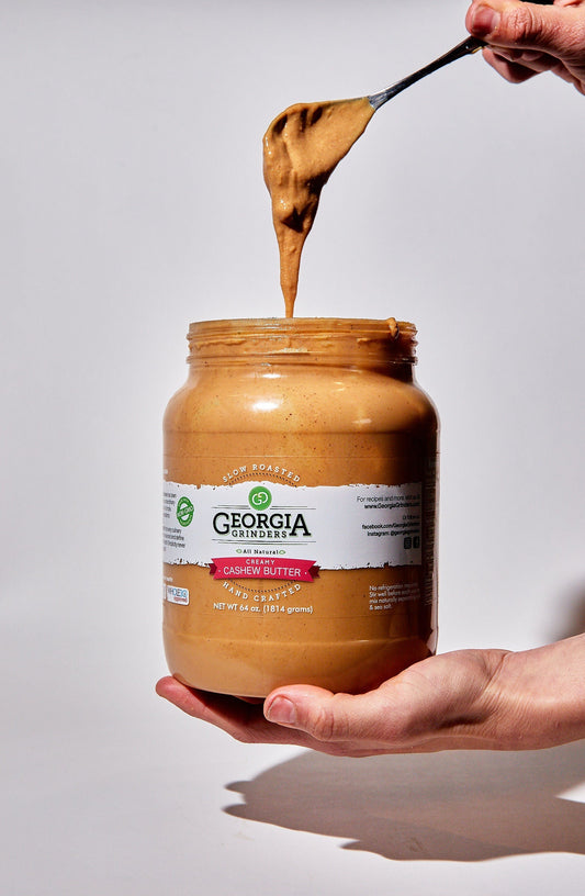 Georgia Grinders 64 oz cashew butter in a large tub, creamy nut butter with a smooth texture and natural light color.
