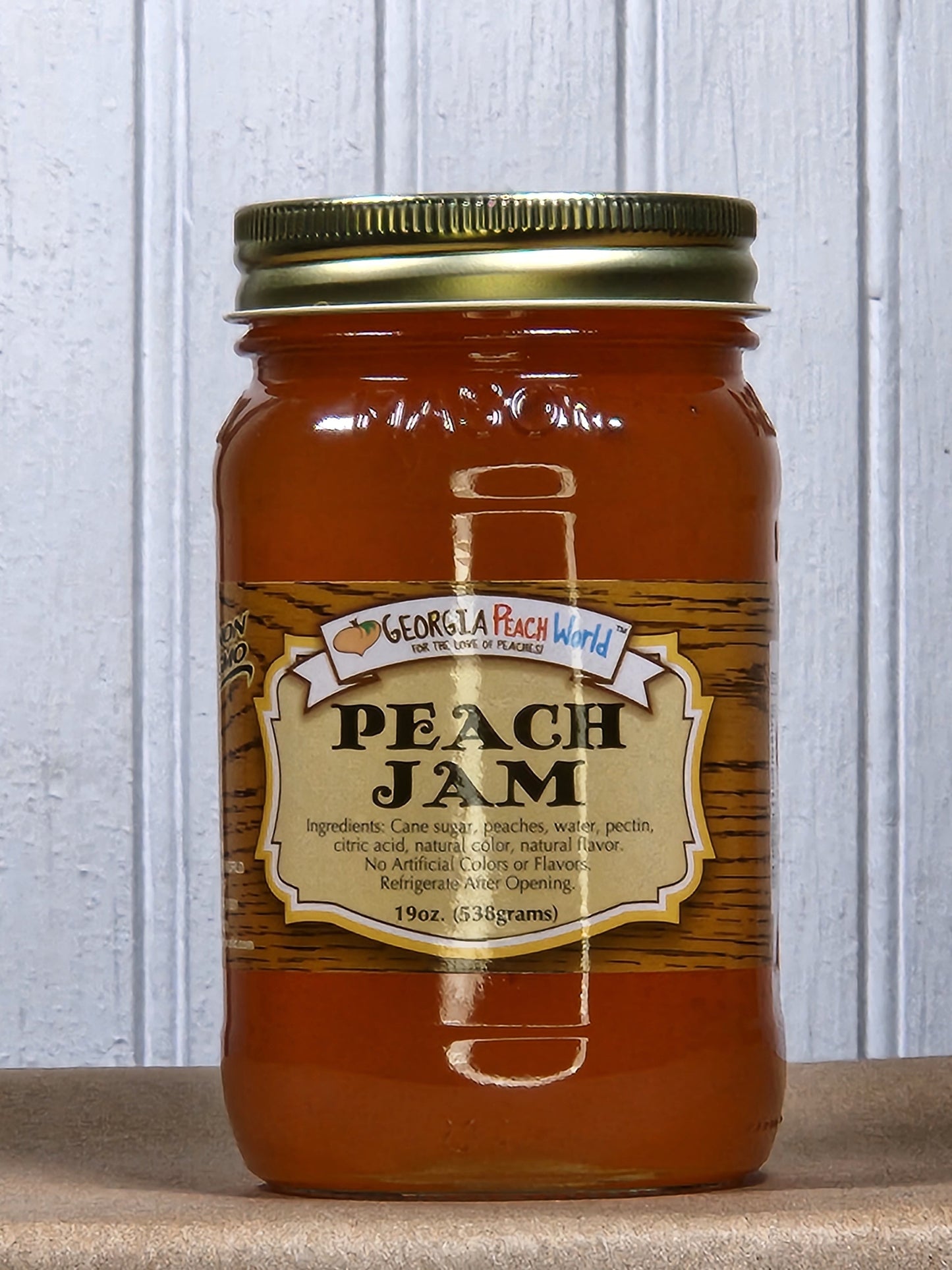 Jar of Georgia Peach World peach jam with a label showing fresh peach images and vibrant orange color.