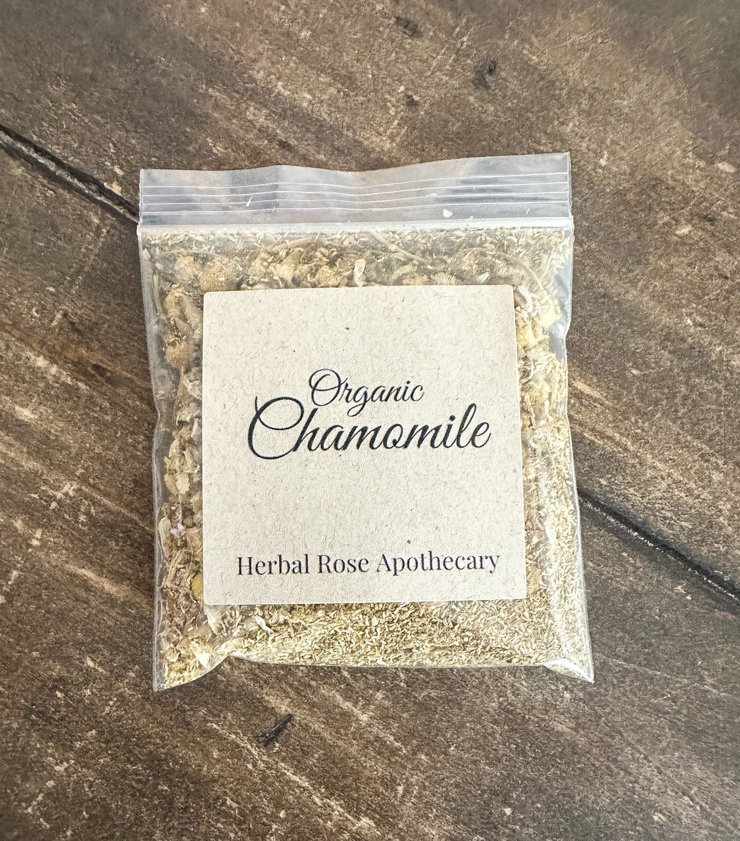 Dried organic chamomile herbs in a clear jar, showcasing yellow and white chamomile flowers from HerbalRoseApothecary.
