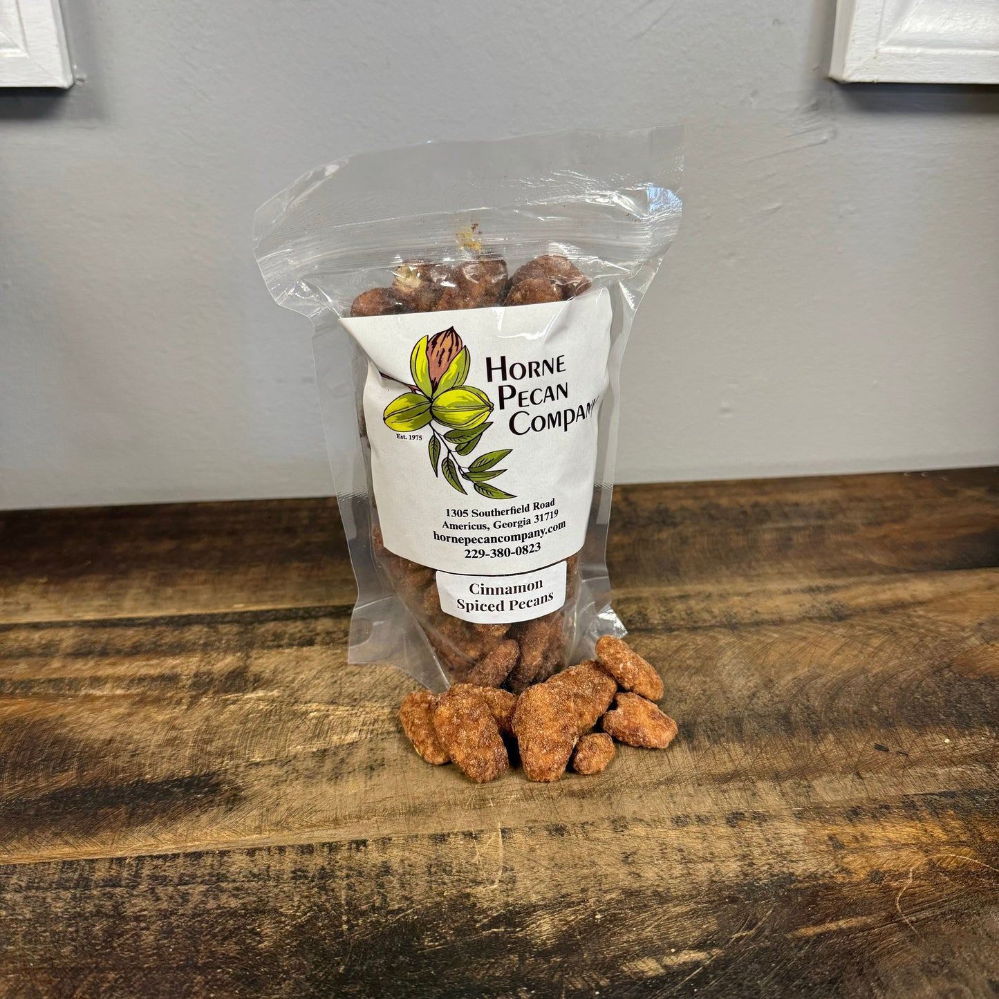 Bag of Horne Pecan Company cinnamon spiced pecans in clear packaging, showcasing glossy, caramelized pecans with cinnamon coating.