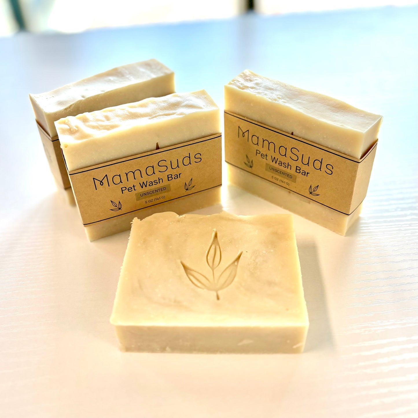 Four rectangular MamaSuds Pet Wash Bar Unscented soaps are arranged on a white surface, with one bar in front displaying an embossed leaf design.