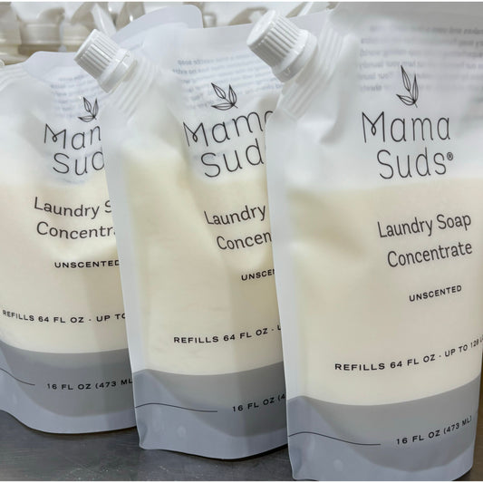 Three 16 fl oz (473 mL) MamaSuds Laundry Soap Concentrate Pouches, unscented and biodegradable with recyclable packaging, are lined up. Each features a white and beige design with a black cap.