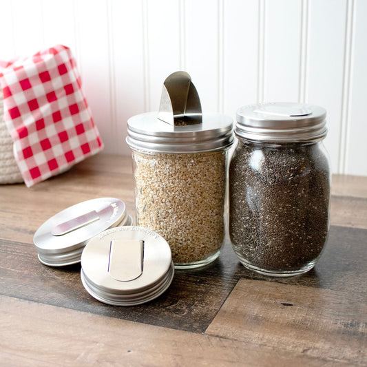 Two stainless steel grain dispenser lids for regular-mouth Mason jars, designed by Mason Jar Lifestyle.