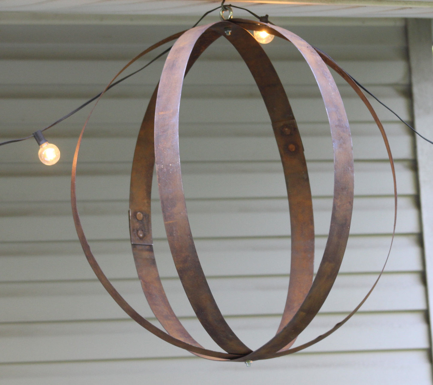 Rustic outdoor hanging plant holder made from reclaimed whiskey barrel rings, crafted by AmishToyBox.com, for garden decor.