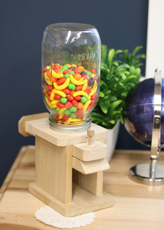 Toy jar candy dispenser from AmishToyBox.com, designed for M&M's, peanuts, or jelly beans, with a clear container and playful design.