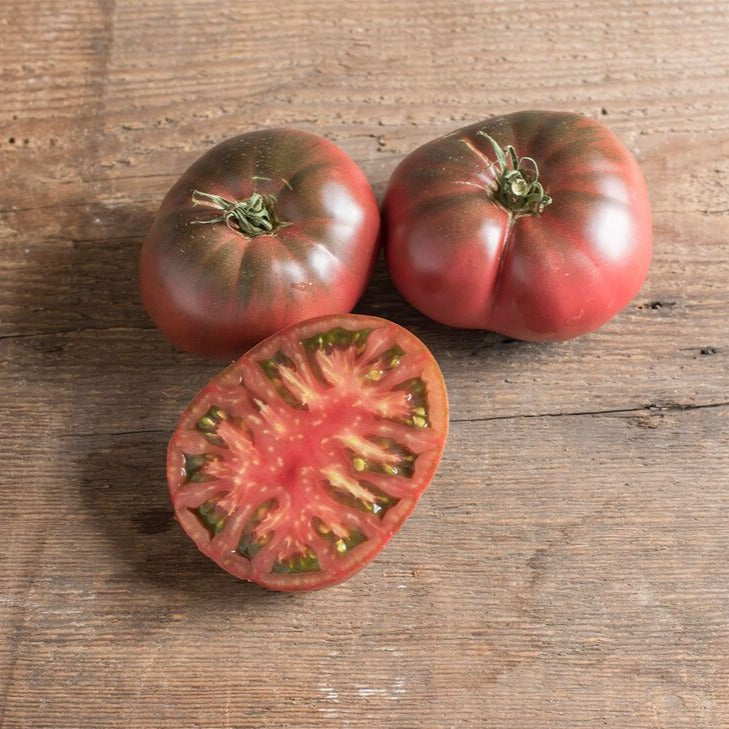 Black Krim tomato from MIgardener, showcasing ripe, dark purple-black heirloom tomato with a smooth, glossy skin.