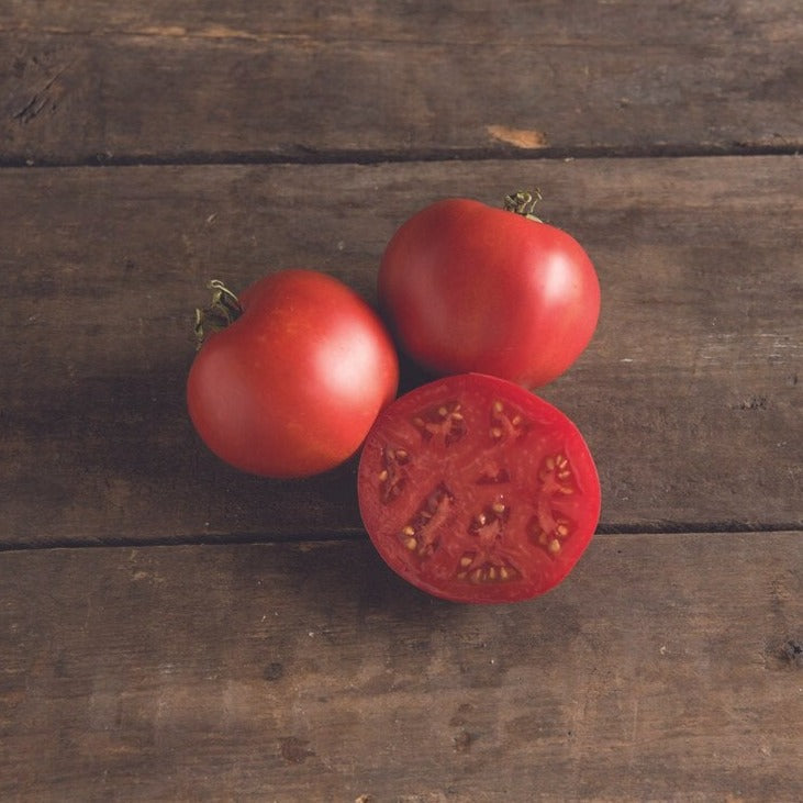 Red Moskvich tomato from MIgardener, showcasing a ripe, round tomato with smooth skin on the plant.