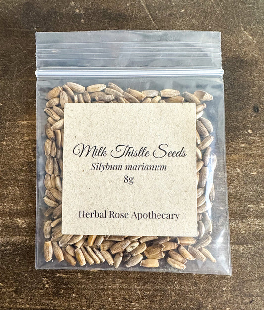 Dried milk thistle seeds from HerbalRoseApothecary, 8g, showing small, dark herbal seeds on a white background.