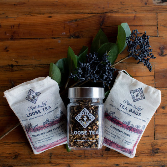 Glass jar of Piper and Leaf Elderberry Elixir loose leaf tea, showing dried elderberries and tea leaves inside.
