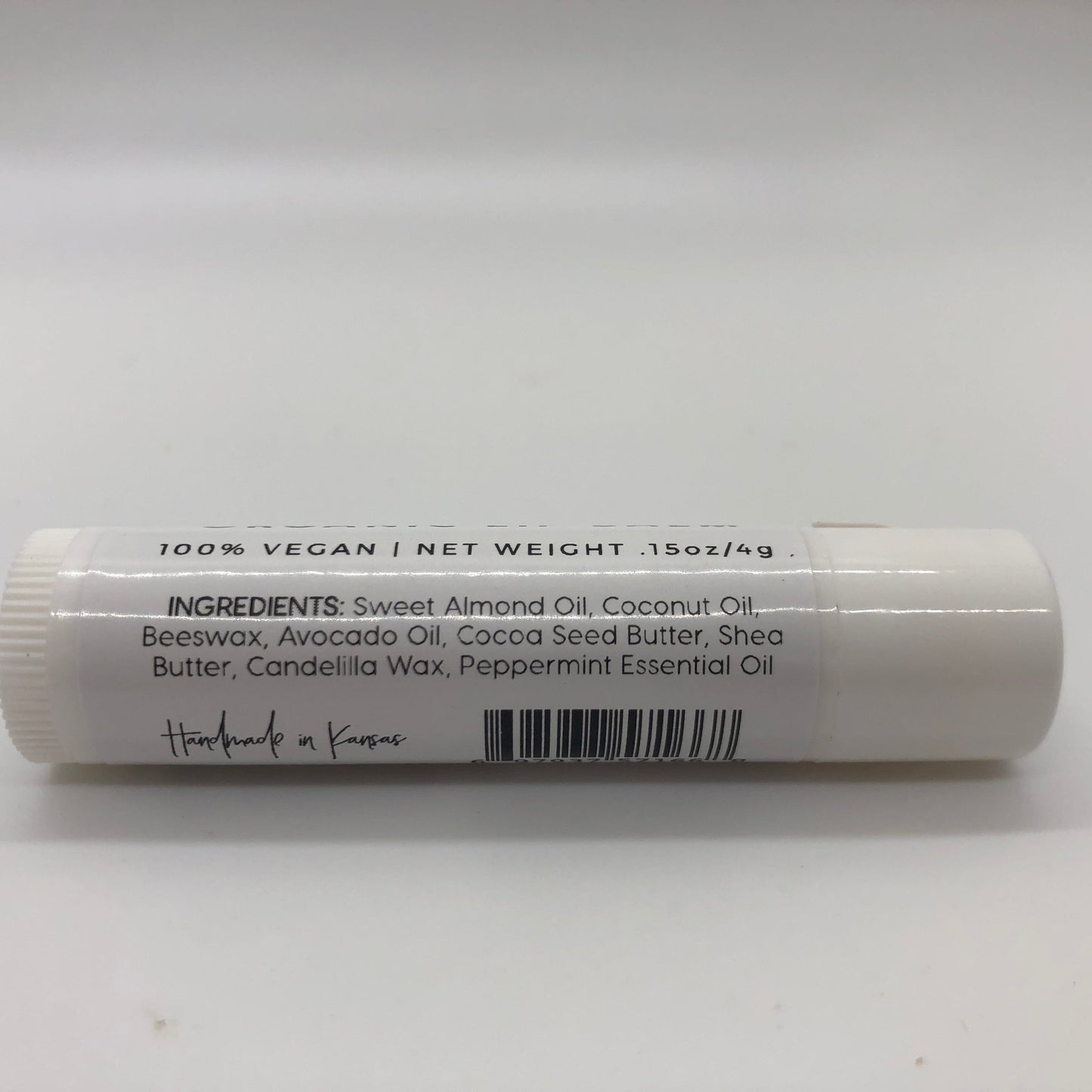 Peppermint lip balm stick from Prairie Fire Tallow with a white tube and mint leaves in the background.