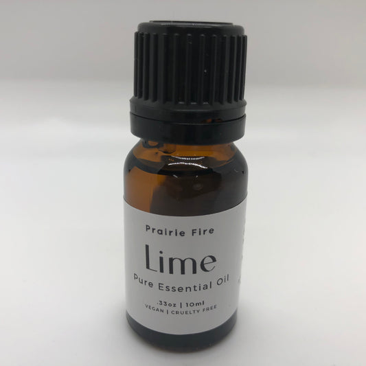 Lime essential oil in a 10 ml bottle from Prairie Fire Tallow, Candles, and Lavender, with fresh green lime slices beside the bottle.