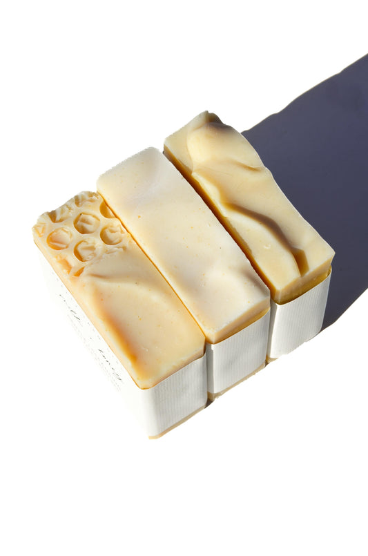 Three fragrance-free handmade soap bars with tallow and goat milk from Pretty Farm Girl, displayed together on a wooden surface.