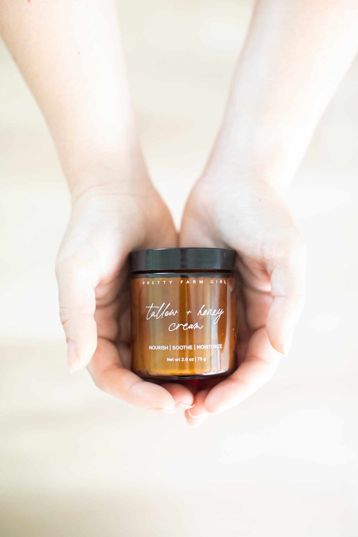 Cream jar labeled Pretty Farm Girl Fragrance-Free Tallow + Honey Cream for sensitive skin, showing the product packaging and texture.