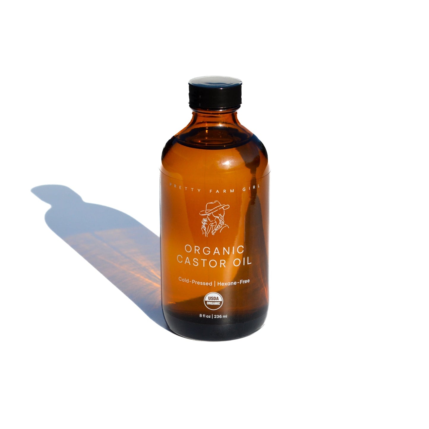 Pure organic cold pressed castor oil in a clear bottle, from Pretty Farm Girl, showcasing the hexane-free essential oil product.