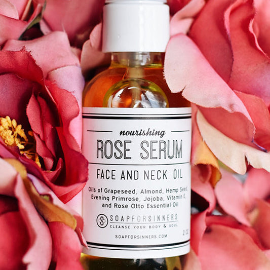 2oz bottle of Soap for Sinners Rose Serum oil, featuring a clear glass container with a rose-colored liquid inside.