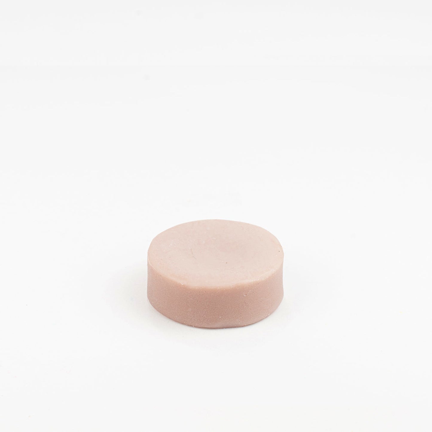 The ZeroWasteStore.com Conditioner Bar, a round light pink bar on a white background, provides a sulfate-free and gentle hair care solution.