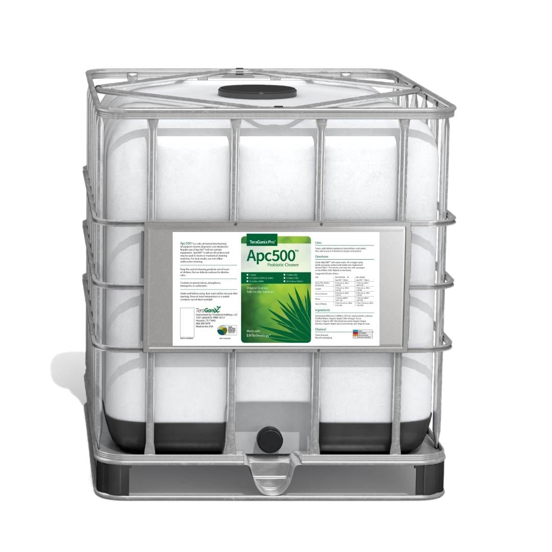A large white industrial container with a metal cage, labeled APC500 by TeraGanix, is designed for bulk liquid storage. Its label shows green text, an aloe image, and notes it as USDA certified organic nontoxic all-purpose cleaner.