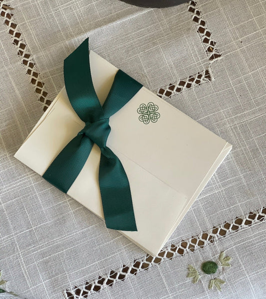 The Celtic Farm’s Boxed Celtic Knot Stationery includes 10 Irish note cards and envelopes, each featuring a small Celtic Clover Knot and dark green ribbon for an elegant touch. Made from recycled paper on an embroidered tablecloth.