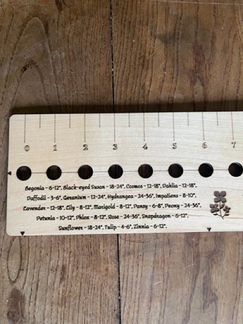 The Celtic Farm’s American Hardwood Seed and Bed Ruler, made in the US from American lumber, features engraved flower names and recommended spacing by each measuring hole—perfect for precise seed planting.