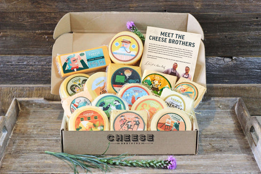 Assorted Wisconsin cheese sampler gift box from Cheese Brothers, Inc., featuring a variety of local cheeses on a wooden platter.