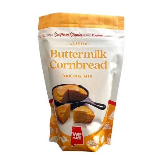 Box of WE Made Buttermilk Cornbread Mix with prepared batter in a bowl on a wooden surface.