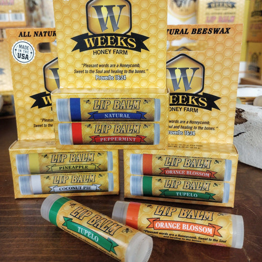 Weeks Honey Farm All Natural Beeswax Lip Balms are available as singles, twin packs, or by the case—featuring flavors such as peppermint and coconut pie—displayed before yellow honeycomb boxes for soft, protected lips.