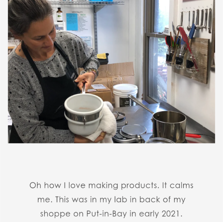 A woman in an apron works with equipment in a lab, holding a container with a towel. Various tools hang on the wall behind her, and jars and supplies sit on the counter.