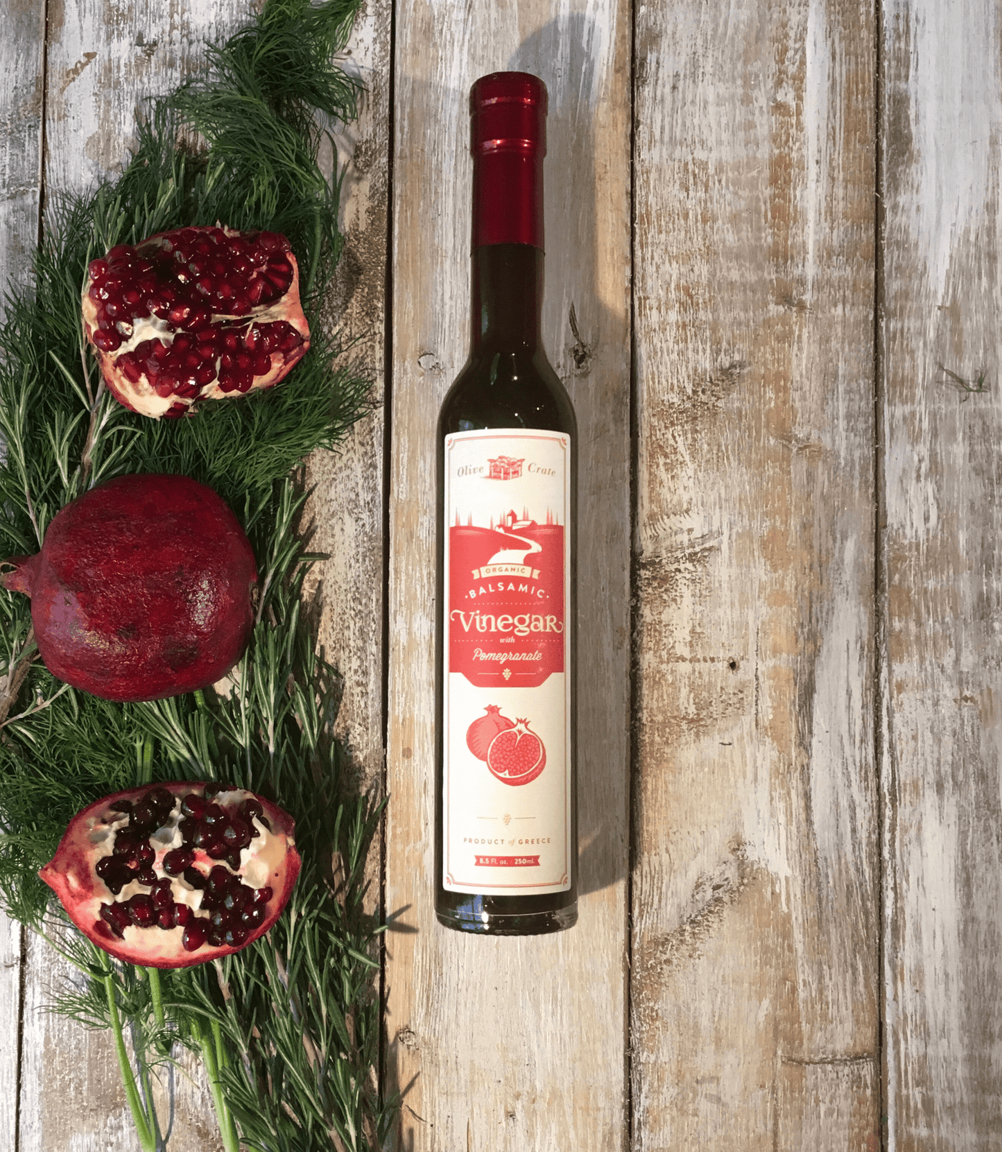 Organic balsamic vinegar with pomegranate in a glass bottle, rich amber color, produced by Olive Crate, ideal for salads and cooking.