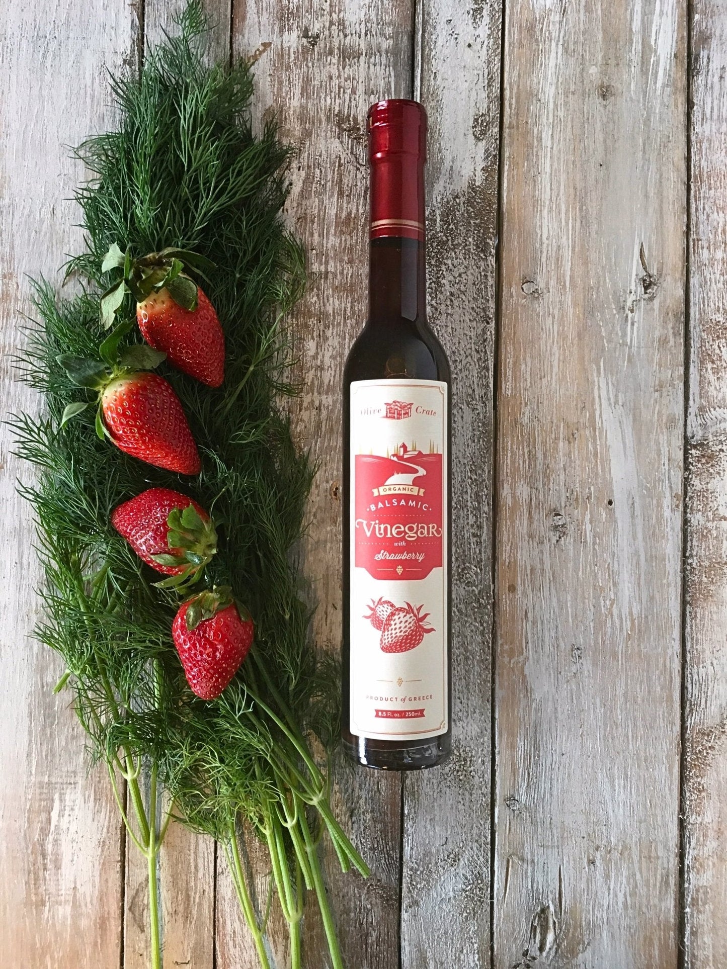 Organic balsamic vinegar with strawberry in a glass bottle, from Olive Crate, showcasing fresh strawberries and dark balsamic liquid.